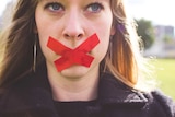 A woman with tape over her mouth.