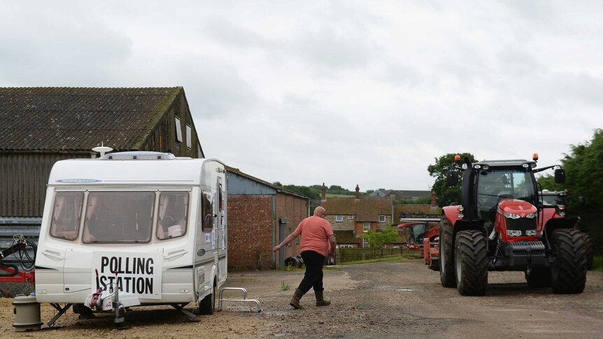 A man leaves a caravan, towards a tractor, which is being used as a polling station on a farm in Leicestershire.