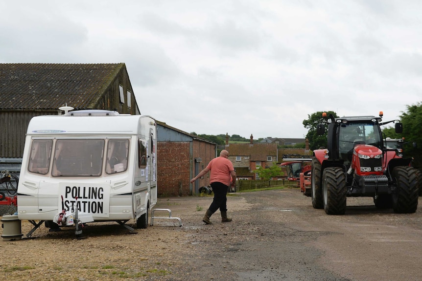 A man leaves a caravan, towards a tractor, which is being used as a polling station on a farm in Leicestershire.