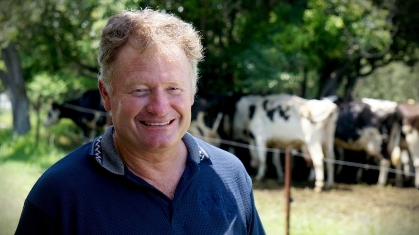 Dairy farmer Craig Tate stands in front of his cows.