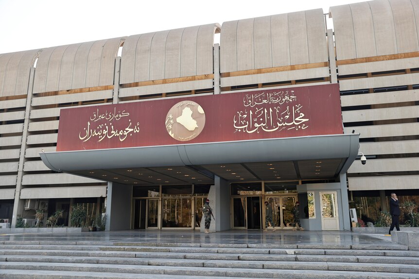 the front of a building with marble stairs and a red sign with gold arabic writing