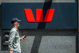 A man holding his mobile phone walks past a Westpac Bank sign in George street Sydney on January 28 2019.