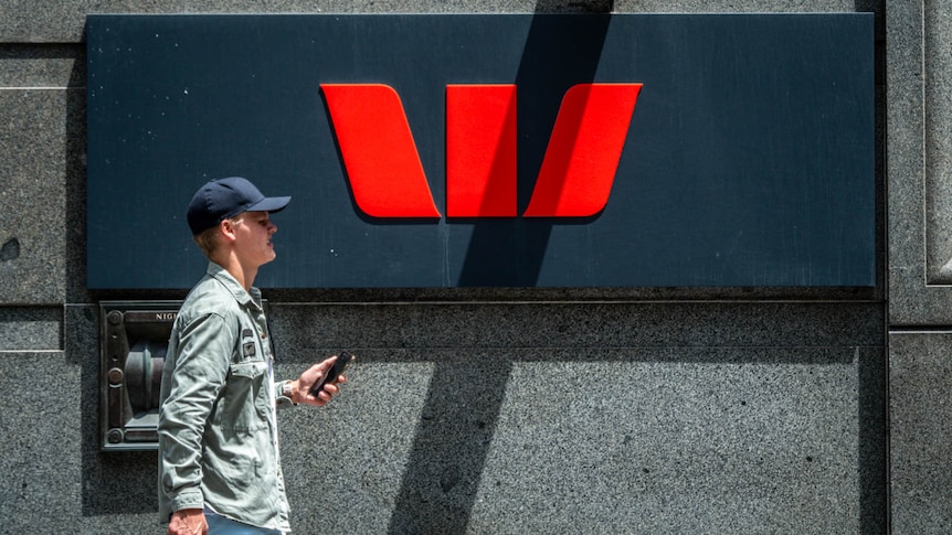 A man holding his mobile phone walks past a Westpac Bank sign in George street Sydney on January 28 2019.