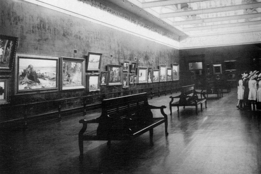 Black and white photo of historic art gallery, girls in white dresses on the right