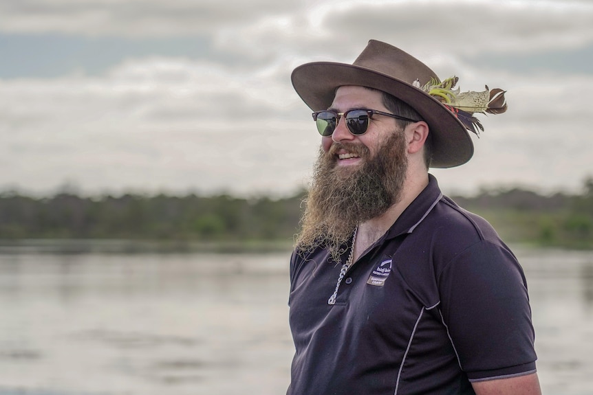 A man smiling in front of a river.