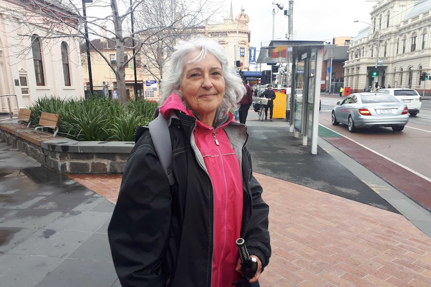 Connie Nikolovski stands smiling at the camera from the footpath on Sydney Road in Brunswick