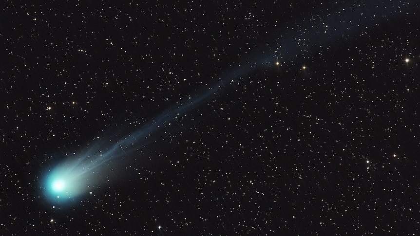 A green comet streaking through a star studded sky