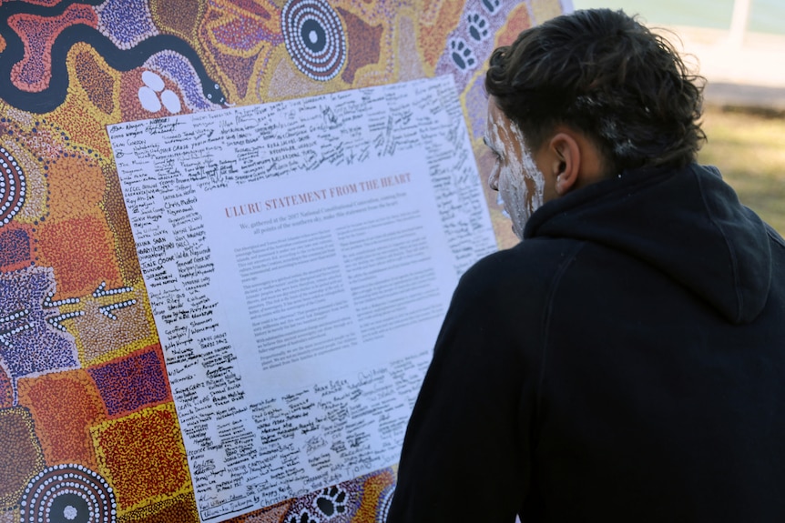 一名原住民女性看着印有乌鲁鲁宣言的面板