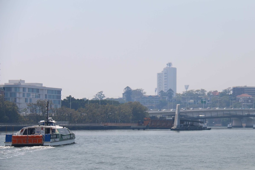 A CityCat travels down the Brisbane River as thick smoke haze hang in the sky.