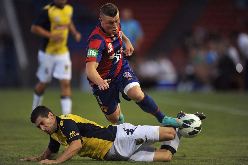 The Newcastle Jets' Dominik Ritter (R) is tackled by the Central Coast Mariners' Nick Montgomery.