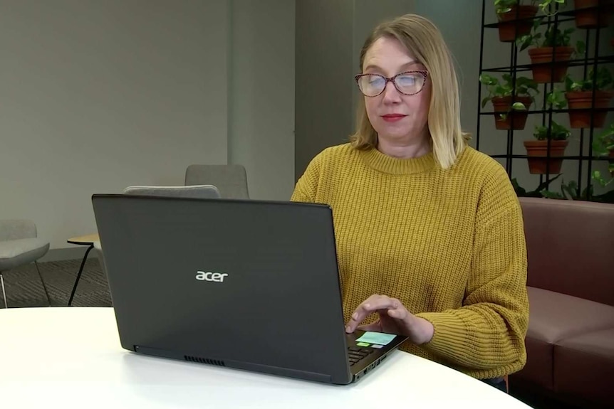 A woman at a table working on a laptop.