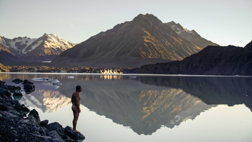 A man standing on the edge of a lake about to swim
