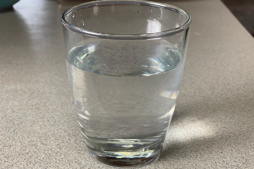 A glass of clear water on a granite kitchen bench.