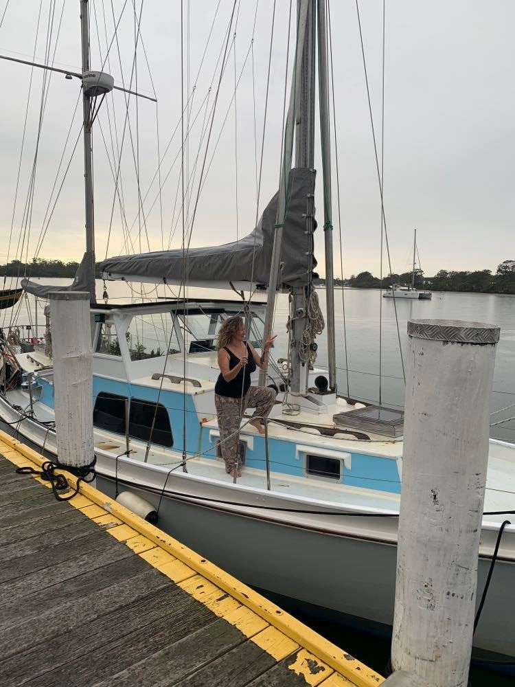 Michelle standing on the side of a boat, holding her fingers in a peace sign.