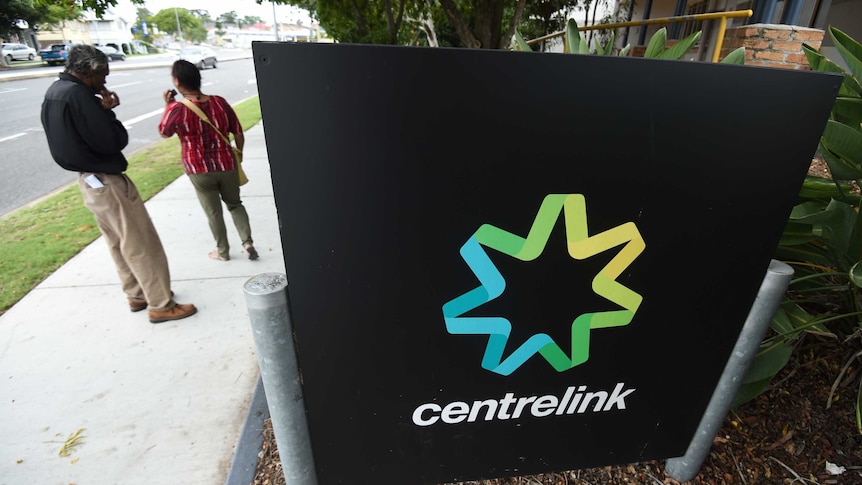 People stand outside a Centrelink office in Brisbane.