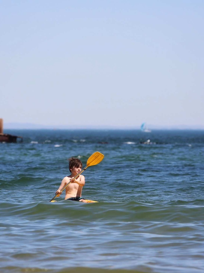 Boy kayaking a beach in Melbourne