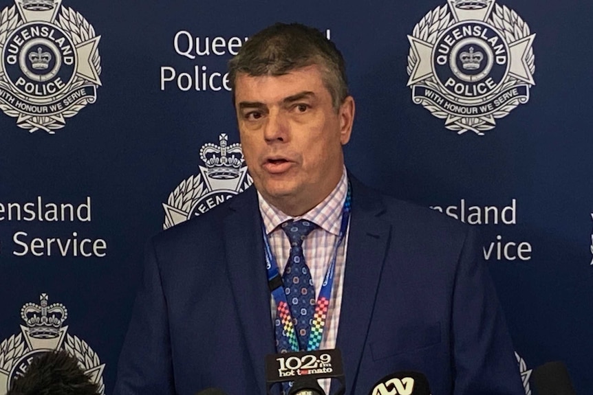 Police detective standing in front of a police backdrop.