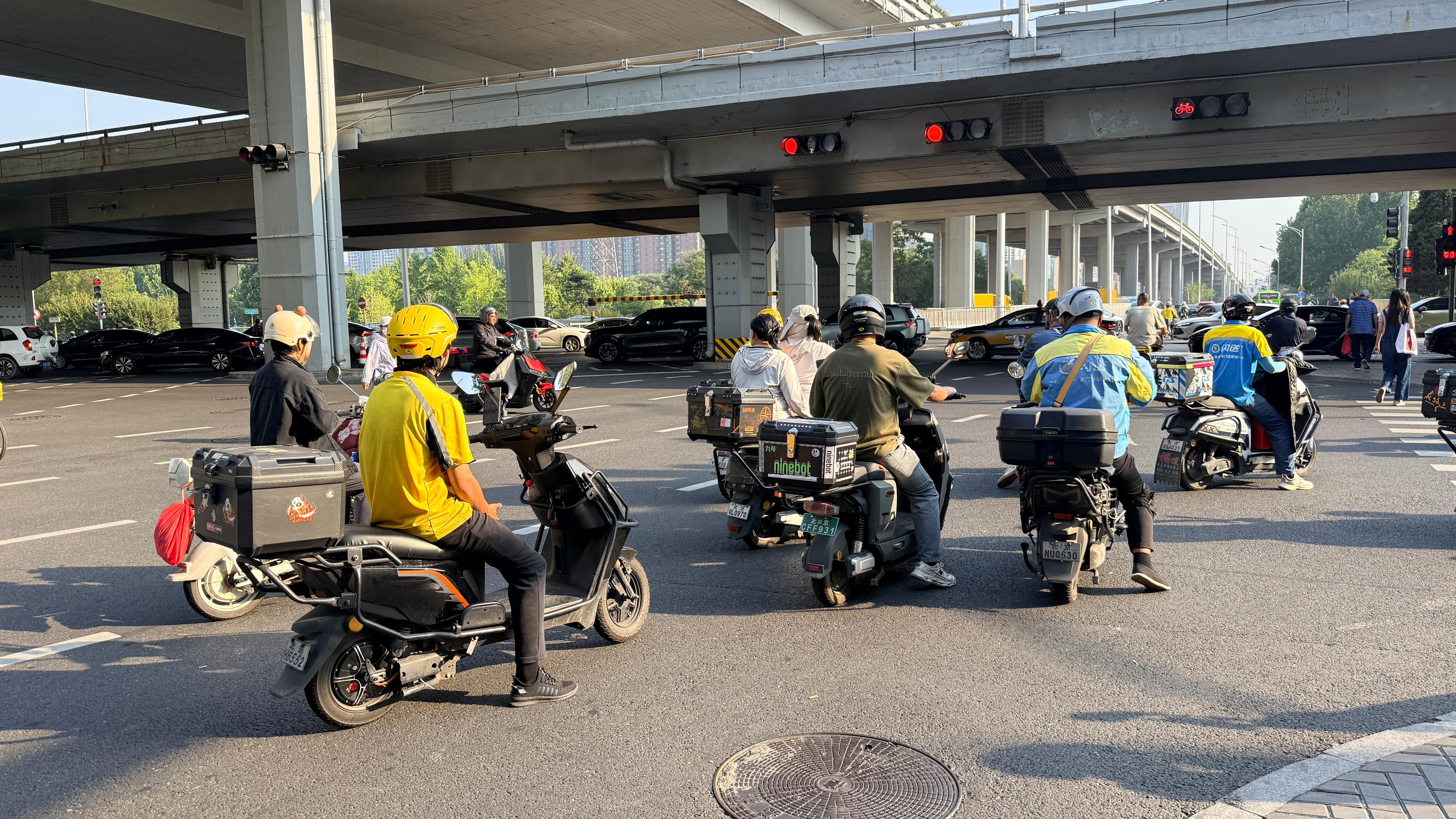 A group of motorbikes waiting at a red traffic light on a big highway.