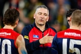 A coach speaks to Melbourne AFL players during a 2023 premiership match.
