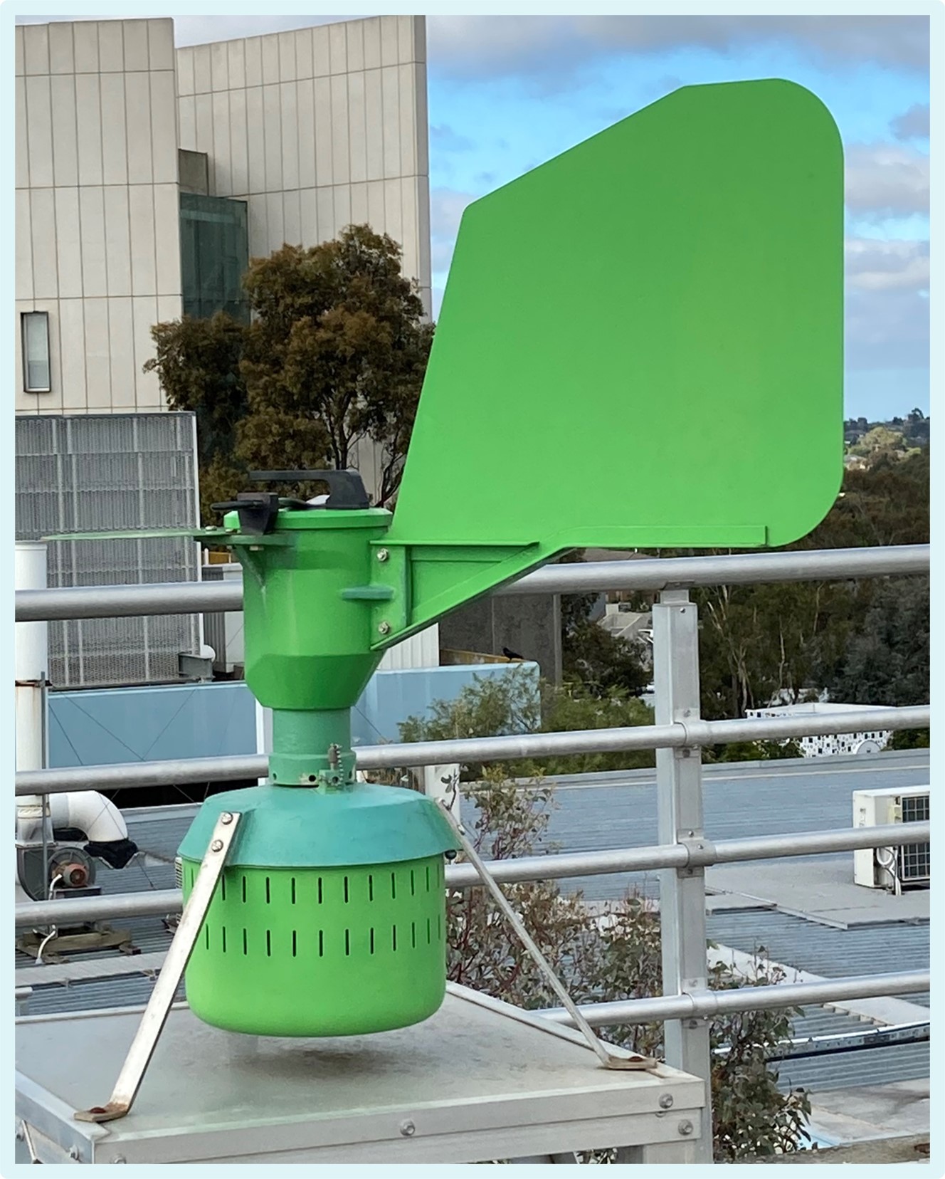 A roof-mounted device with a large green sail and a chamber