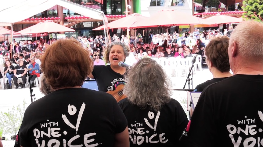 Nicky Johnson conducting a choir outside