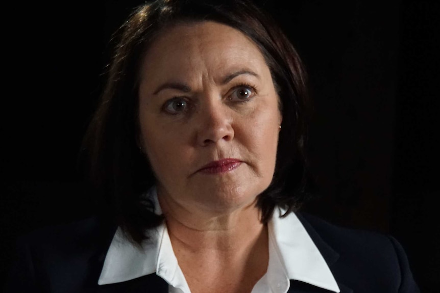 A headshot of Liza Harvey in a black jacket and white shirt.