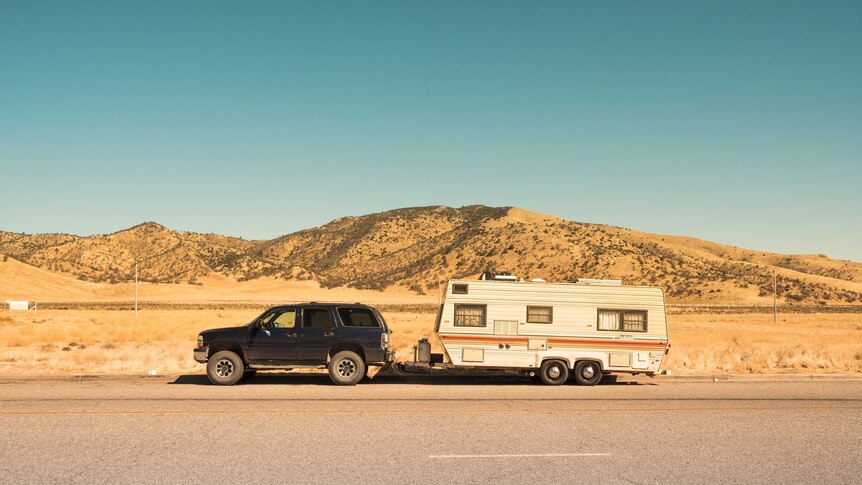 4 wheel drive pulling older style caravan on outback road