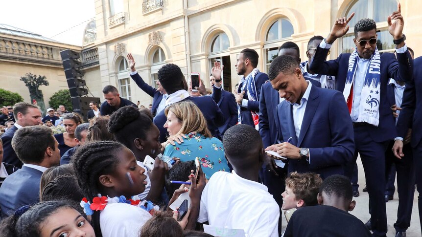 Kylian Mbappe signs autographs for young fans in the Elysee Presidential Palace.