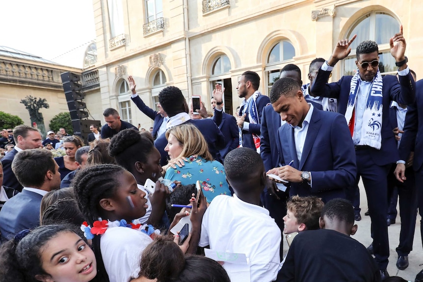Kylian Mbappe signs autographs for young fans in the Elysee Presidential Palace.