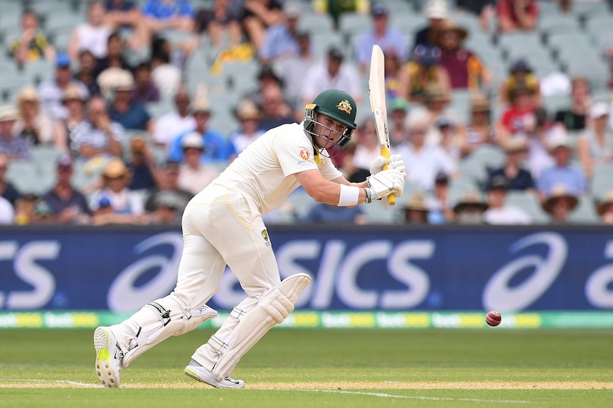 A batsman plays a shot off his pads, leaning forward and looking at the ball