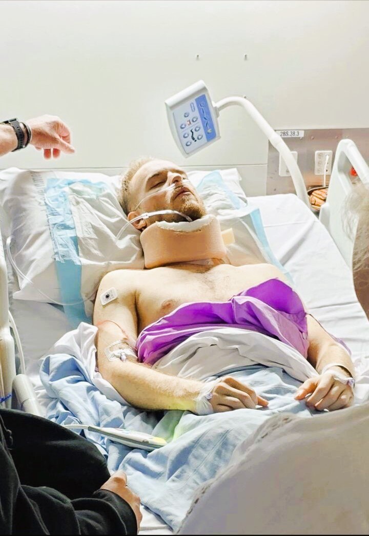 A man laying in a hospital bed in a neck brace.