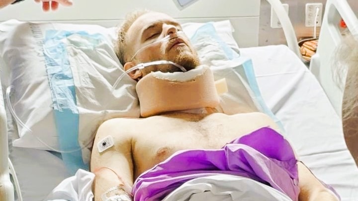 A man laying in a hospital bed in a neck brace.