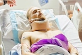 A man laying in a hospital bed in a neck brace.