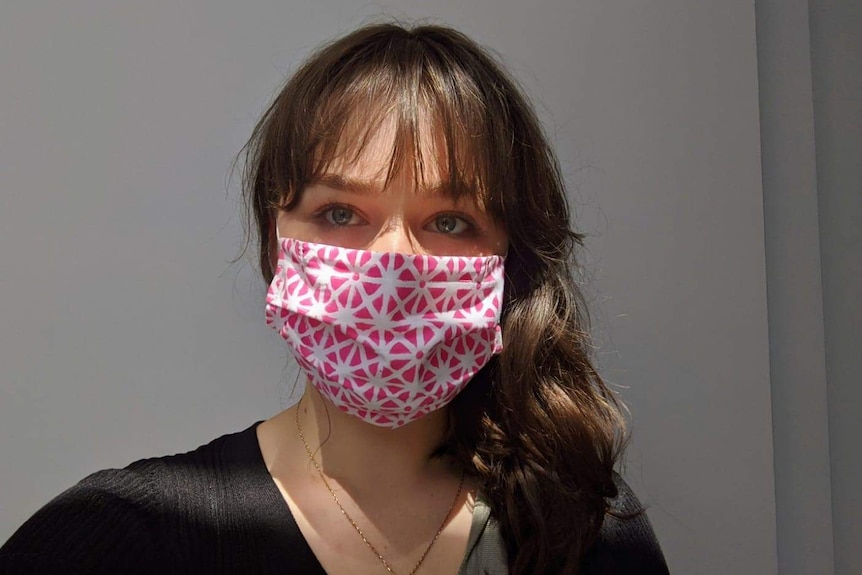 Abby Lehmann wears a pink face mask and has her hair down as she stares into the camera for a selfie.