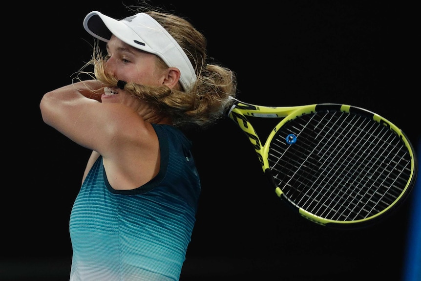 Caroline Wozniacki plays a backhand as her pony tail swings into her nose