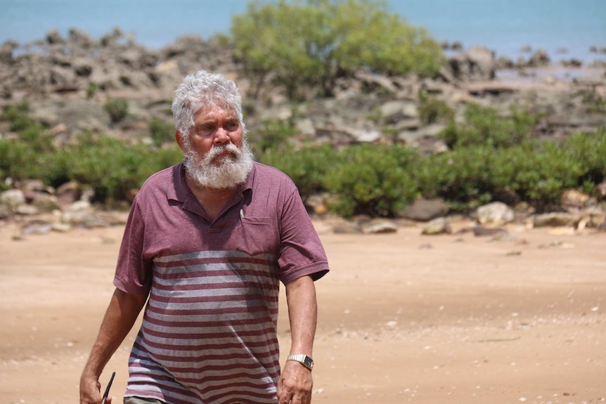 A man walks along a beach.