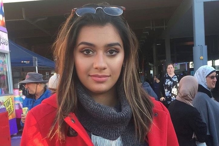 A woman wearing a red jacket with dark hair at a festival.