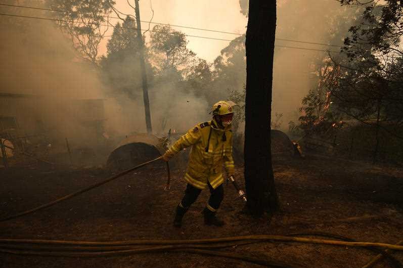 NSW RFS crews work to protect a property in Kulnura from the Three Mile fire.