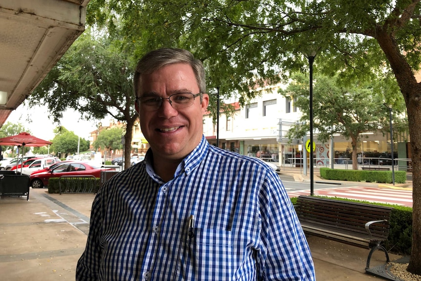 Temora Shire Mayor Rick Firman is wearing glasses and a blue, checked shirt as he stands on street