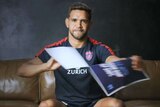 Melbourne football player Neville Jetta tears a sign showing an abusive tweet about him.