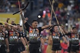 An Aboriginal rugby league player holds up two boomerangs during a pre-match war cry performance
