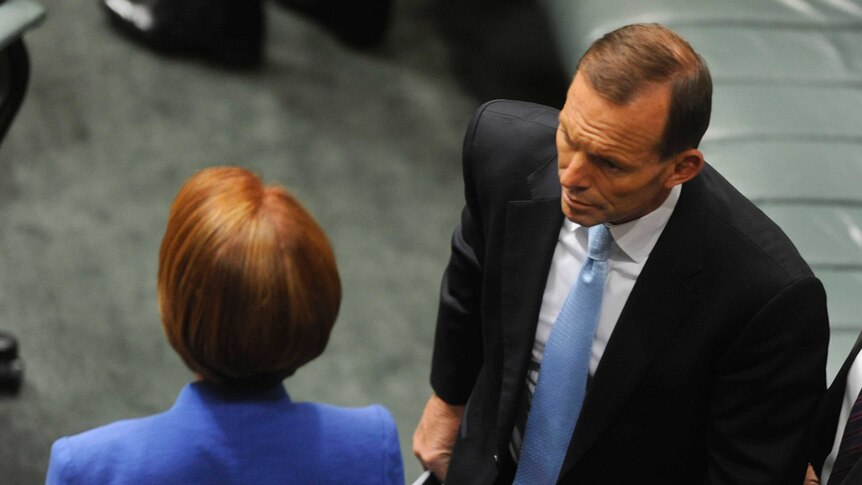 Tony Abbott walks past Julia Gillard