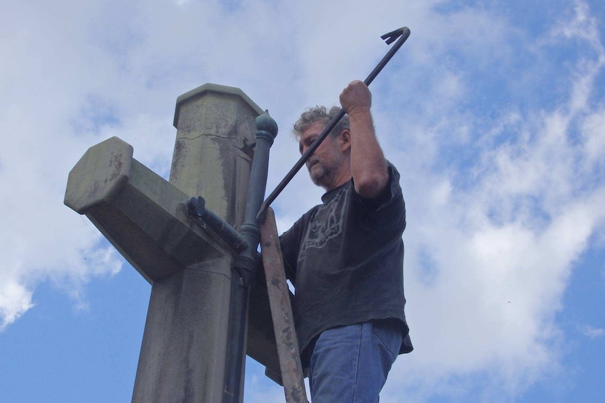 James Downling uses a crowbar to remove the sword from the cross