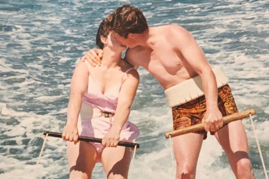 An old photo of a man and a woman kissing while water skiing