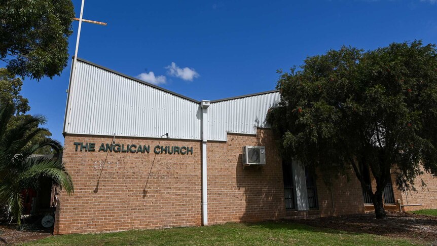 An 80s brick Anglican Church sits against a stark blue sky.