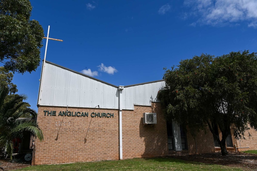An 80s brick Anglican Church sits against a stark blue sky.