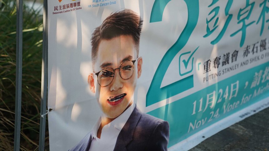 An election sign showing a man with scribbled out eyes and mouth.