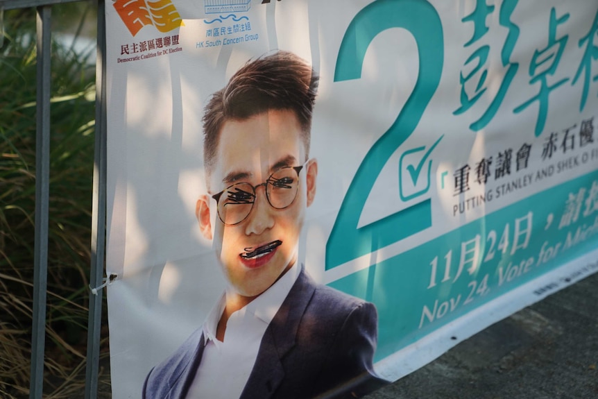 An election sign showing a man with scribbled out eyes and mouth.