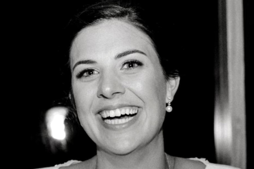 A black and white photo of a smiling Melissa Hoskins in a white dress