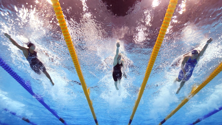 Three female swimmers during a race photographed from underwater